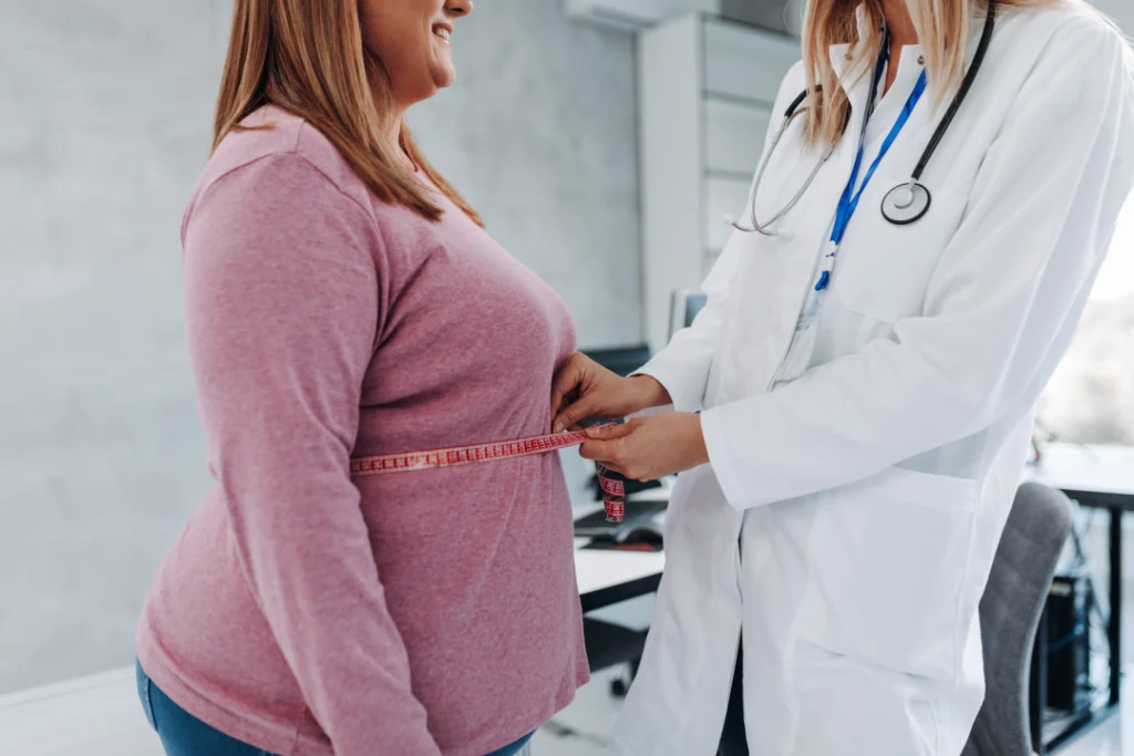 A healthcare professional measuring a patient's waist as part of a tirzepatide weight loss consultation.