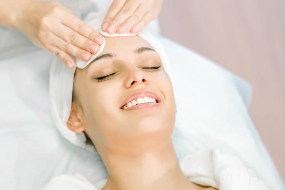 Skincare expert prepares client for chemical peel facial.
