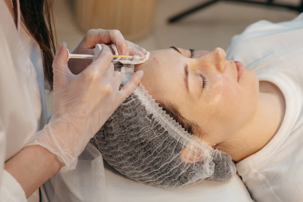 Med spa specialist administering Xeomin injection to a woman’s forehead.