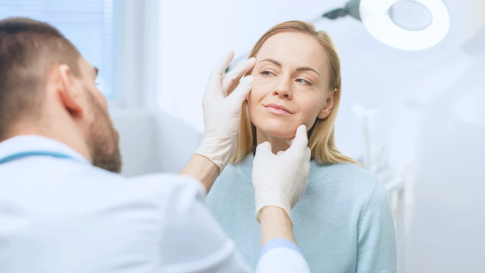 Doctor examining a patient’s face during a PDO threads consultation.