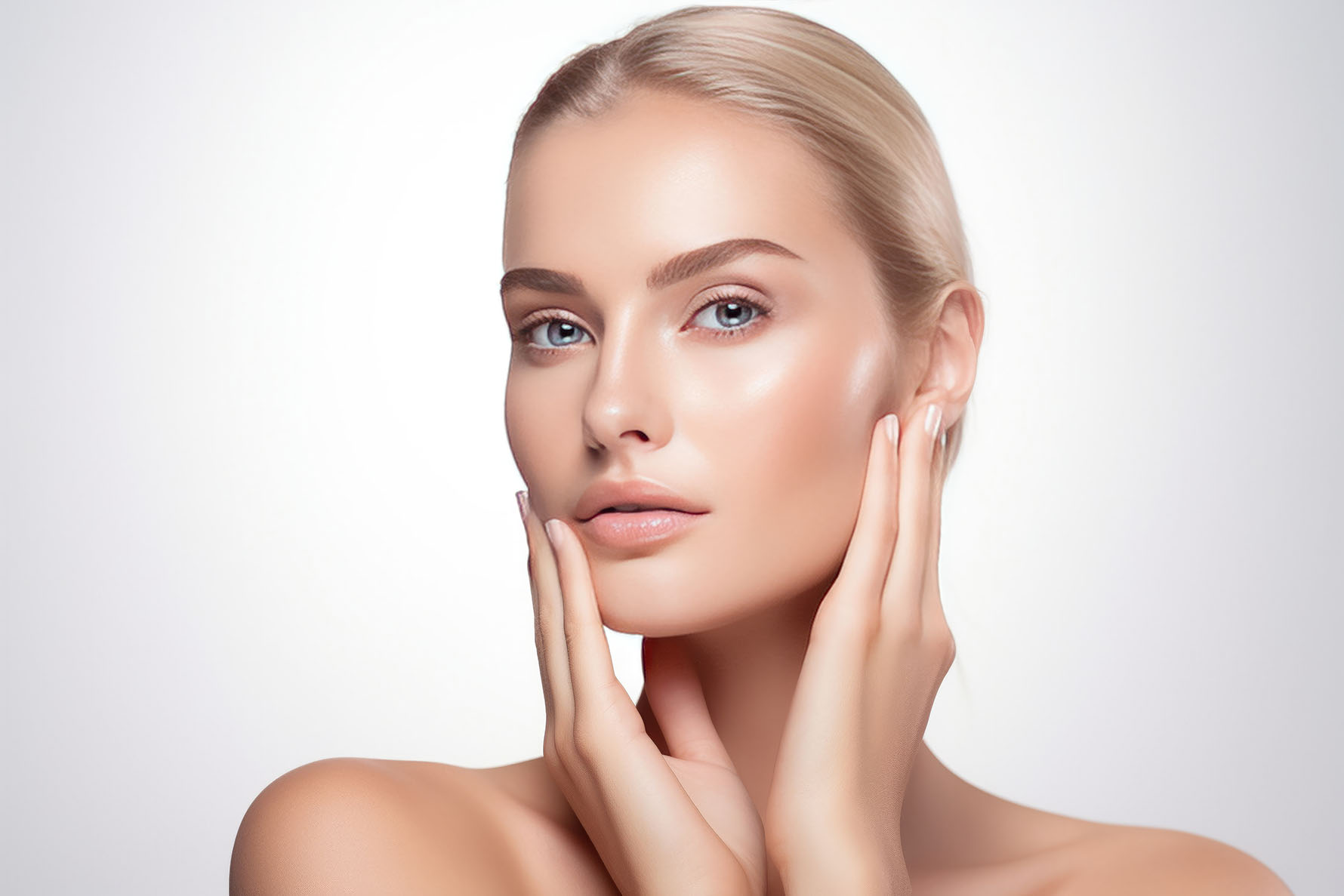 woman with light hair gently touching her face with both hands against a white background