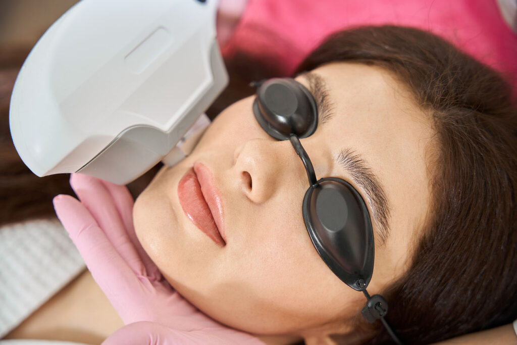 Person lying down wearing black eye shields while a handheld device is positioned near the face.