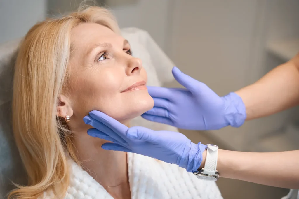 Provider examining a woman’s face during a skincare consultation