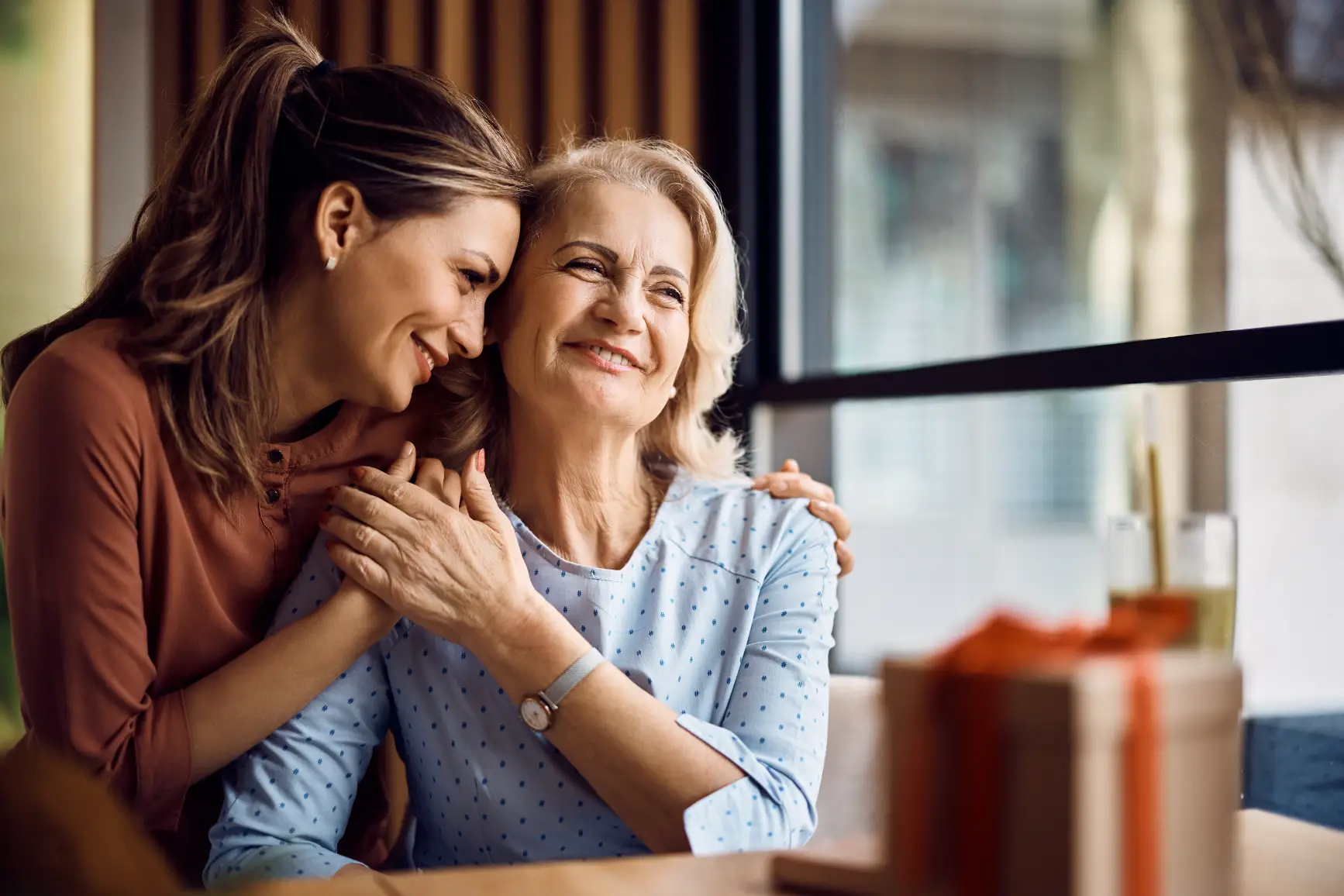 Two women smiling and sitting together in a relaxed indoor setting