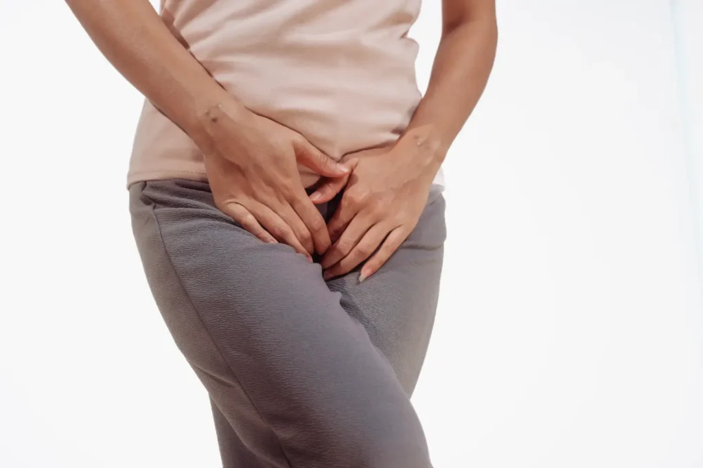 Woman holding lower abdomen while standing in casual clothing