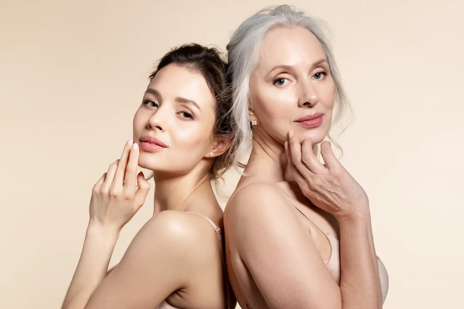Two women of different ages posing together with smooth skin against a neutral background